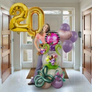 A young girl standing behind a balloon arrangement with flowers, butterflies and large balloon numbers. Salem Oregon balloon delivery