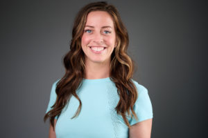 Photo portrait of Chaeli Greco, smiling with a gray background behind her.