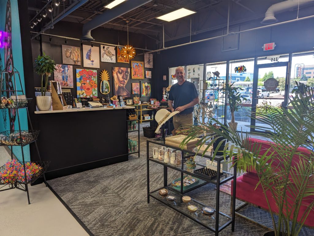 David Triplett of Hawaii Fluid Art stands smiling in the entrance of his shop, surrounded by retail goods.