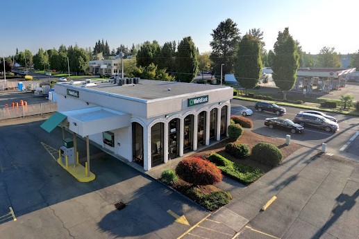 Aerial View of WaFd Bank, North Salem, Oregon - showing parking lot, landscaping, Drive-Thru, and tree-lined Broadway Street running beside it. Morning light streaming in from top right corner of picture - building with arched windows across the front