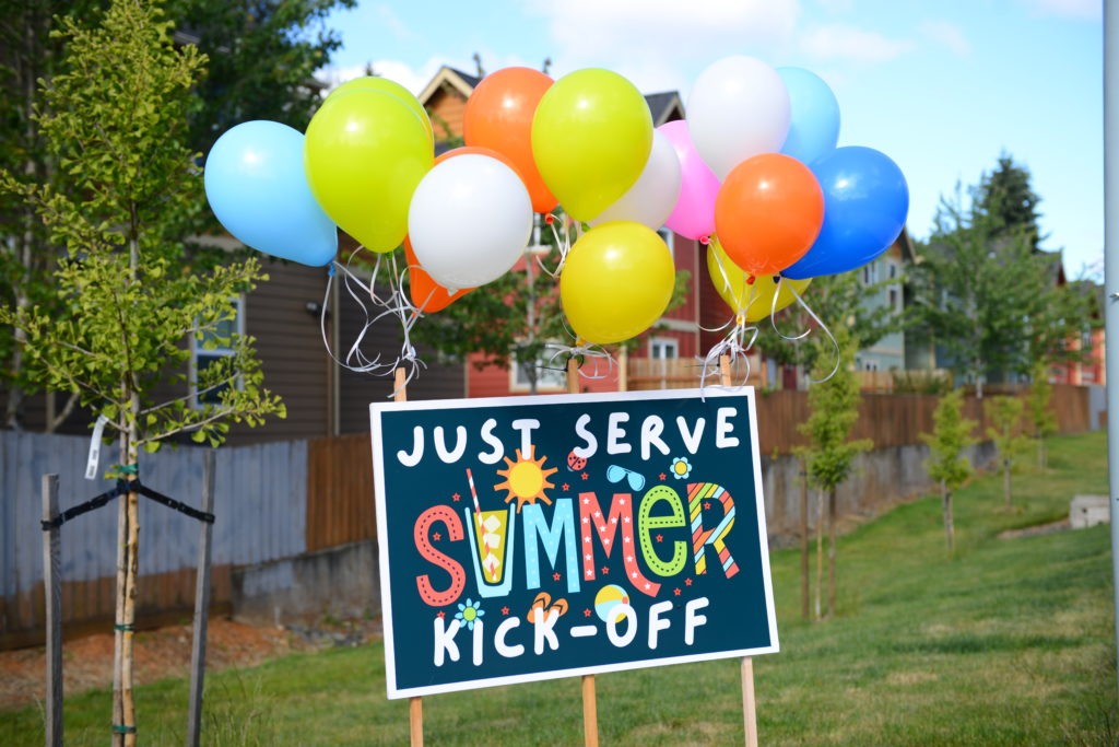 JustServe Summer Kick-off sign with colorful balloons