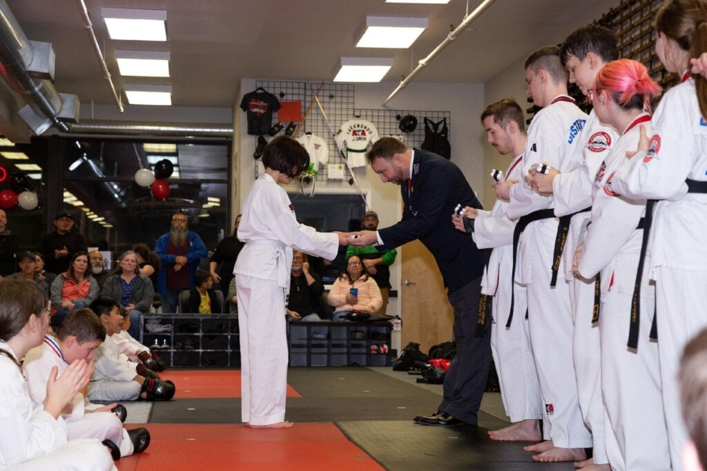 Belt ceremony - student receives new belt from coach