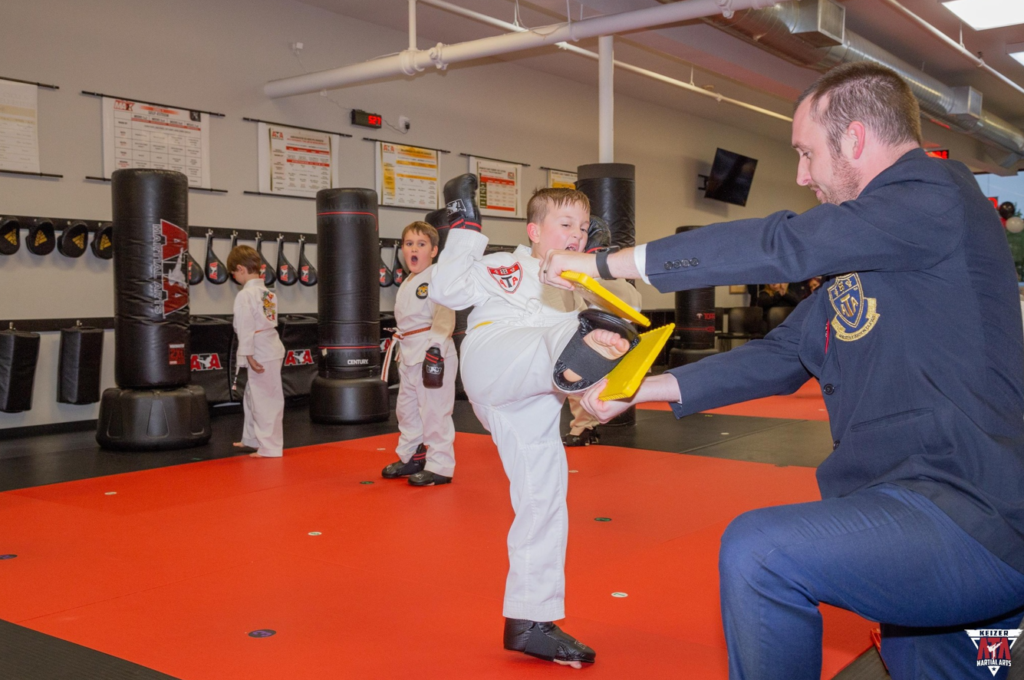 Student kicks a board during Empower ATA Martial Arts Class