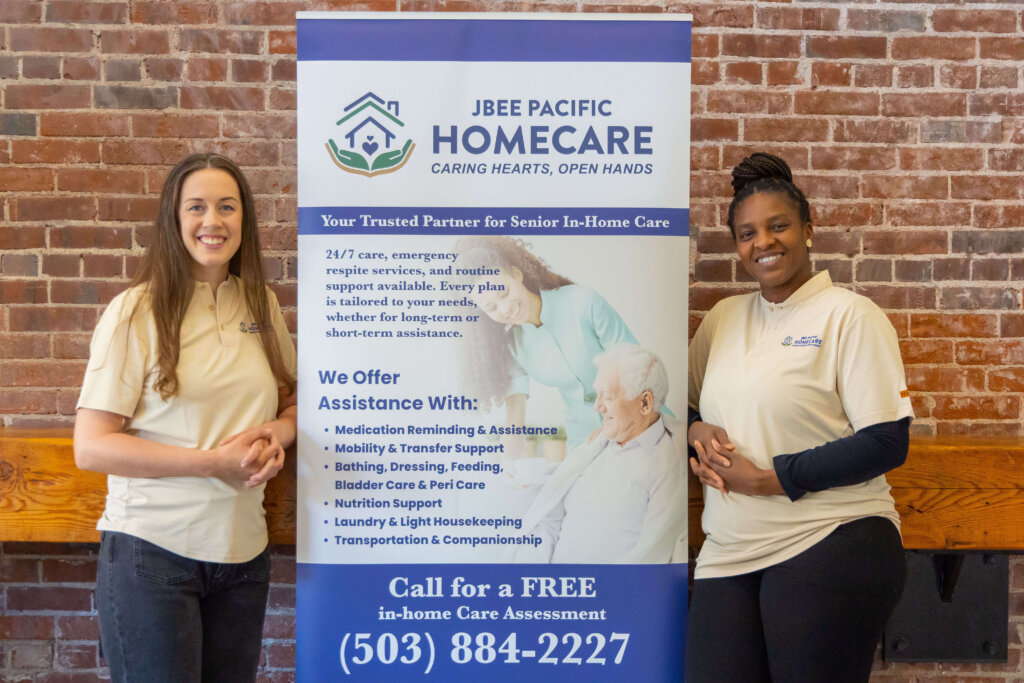 Rebecca and Beatrice standing with JBEE Pacifice Homecare banner