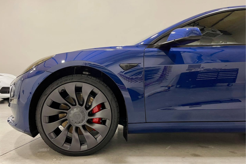 Blue Tesla Model 3 with a glossy vinyl wrap finish.