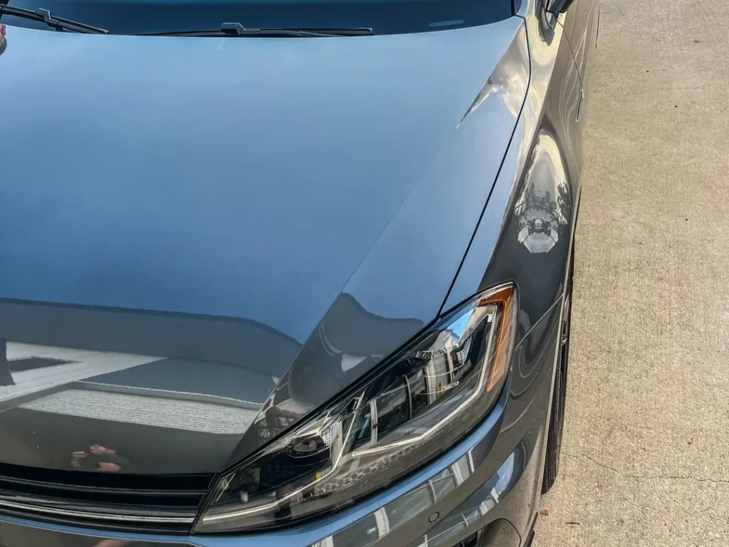 Close-up of glossy grey car hood showing reflections from paint correction in College Park TX.