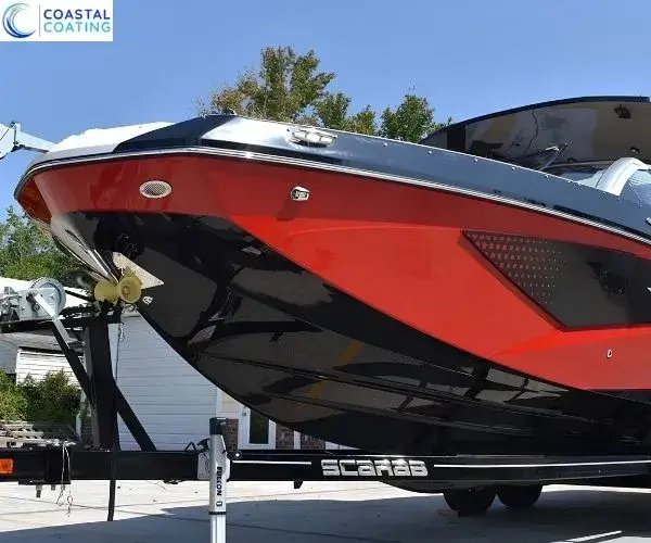 view highlighting the reflective black hull and red upper deck of the Scarab jet boat on its trailer