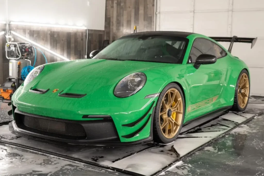 Green Porsche GT3 RS parked inside a wash bay for car detailing in Cumming GA.