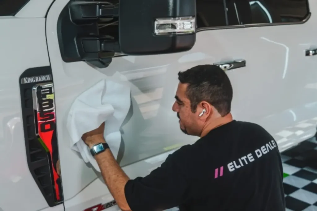 Technician wiping down a white Ford truck during ceramic coating service.
