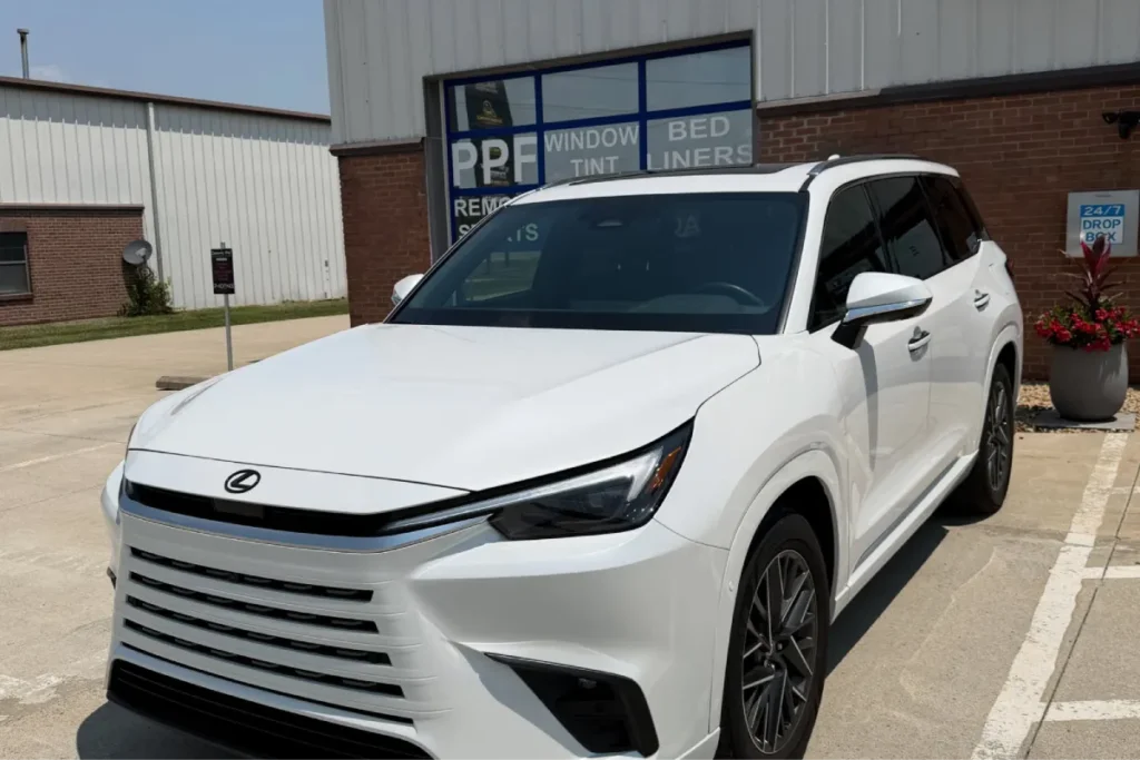 White Lexus SUV parked outside an auto shop for car wraps services.