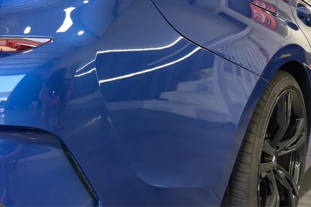 Close-up of glossy blue car paint protected with hydrophobic ceramic coating.