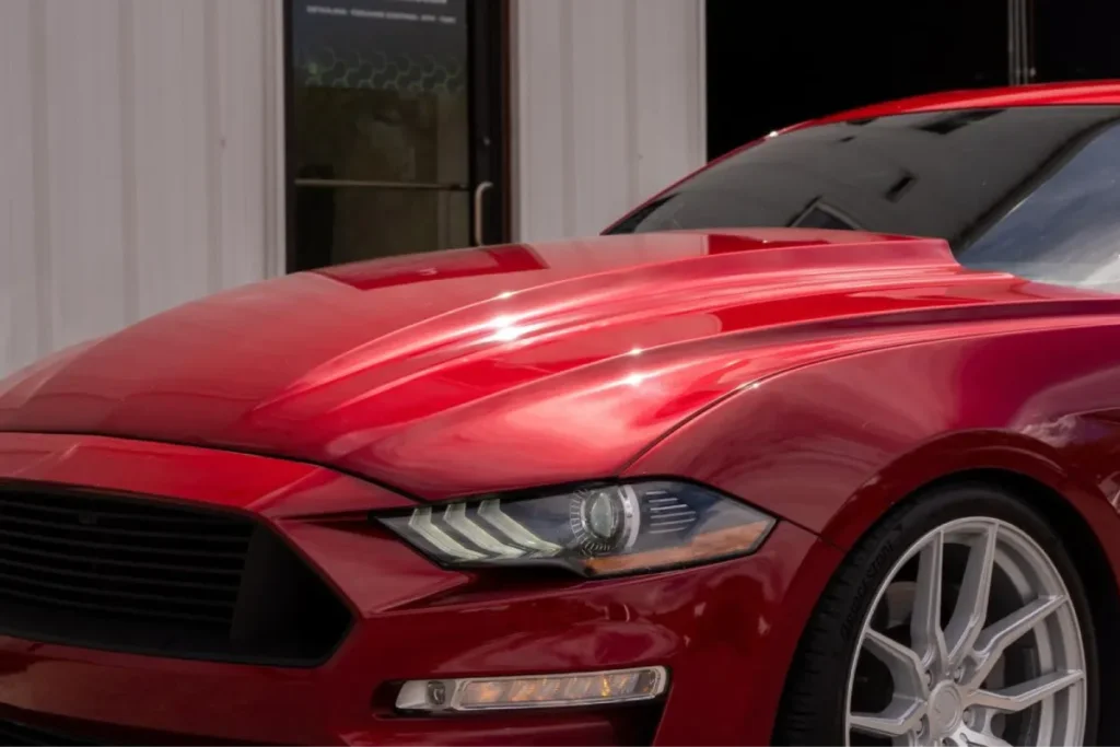 Close-up of a red car hood displaying a glossy protective ceramic coating.