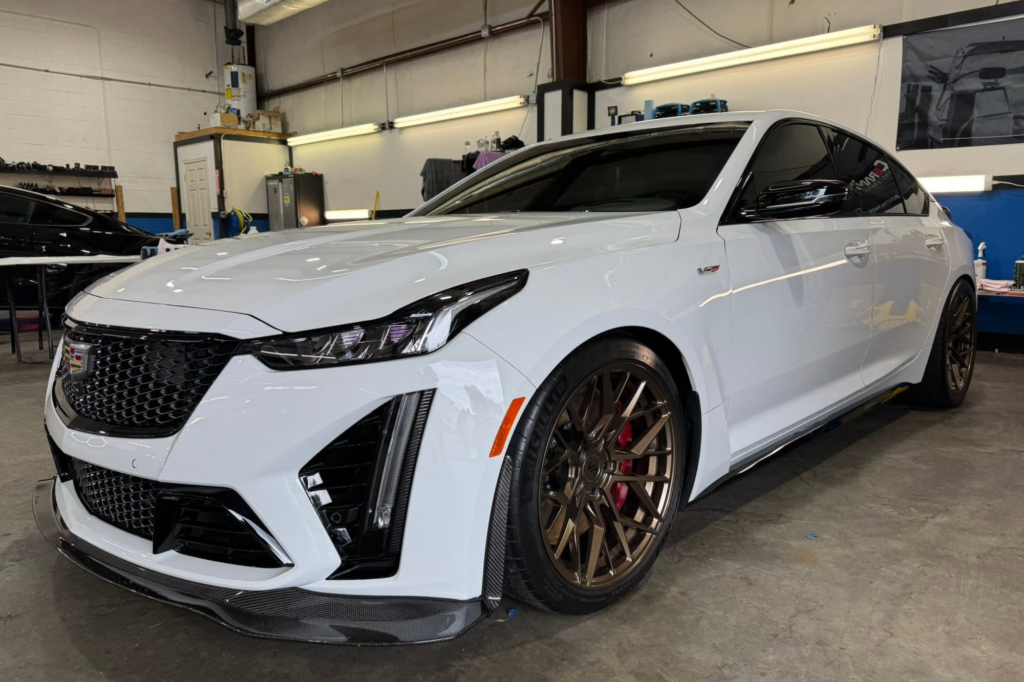 Clean white sedan treated with ceramic coating in Raleigh, NC inside a detailing shop.