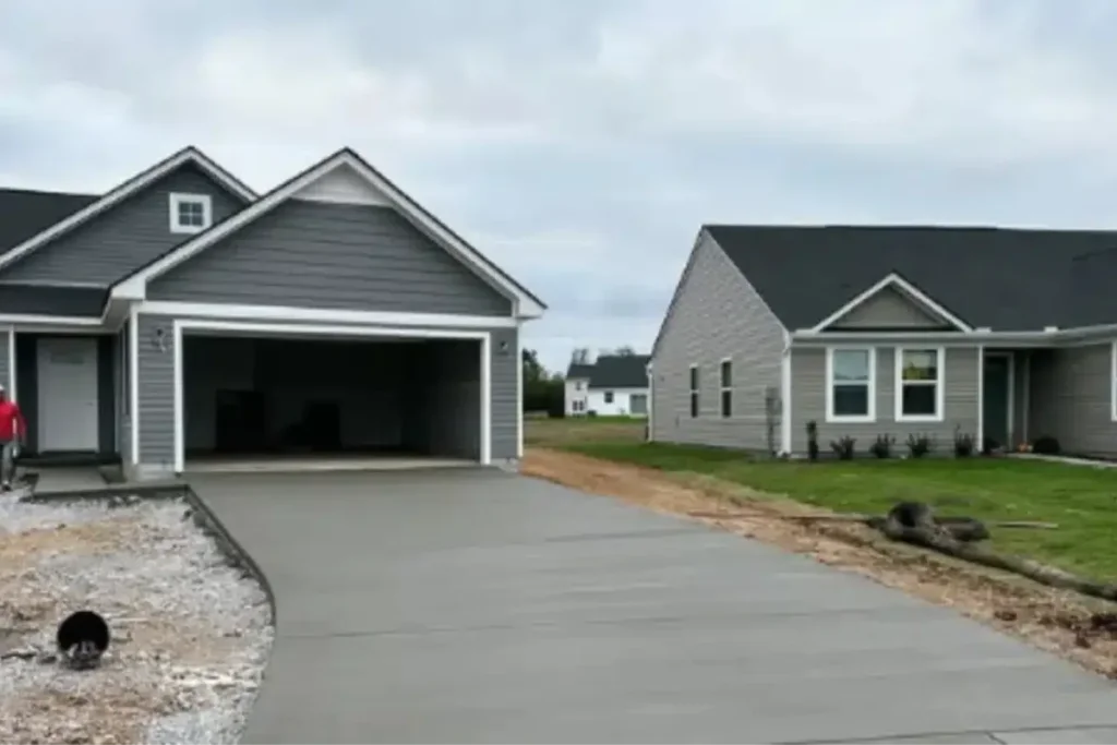 Grey suburban home with an open garage and freshly poured concrete driveway built by a garage builder.