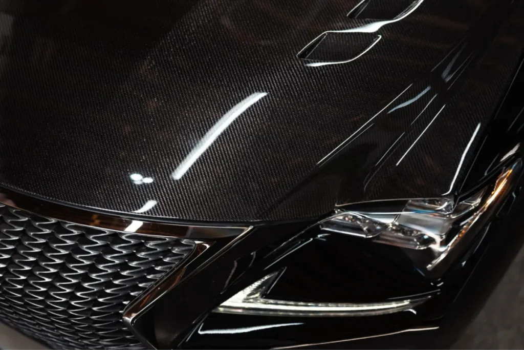 Glossy carbon fiber hood of a black Lexus vehicle after paint correction.