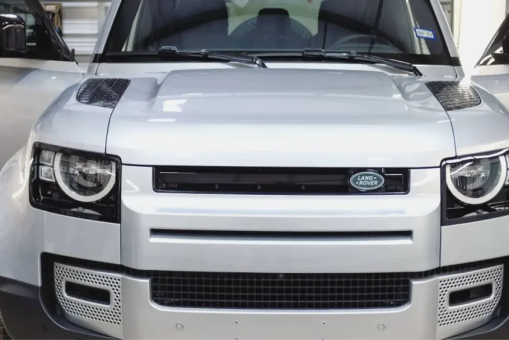 Front bumper and hood of silver Land Rover Defender for paint protection film in Arlington TX.