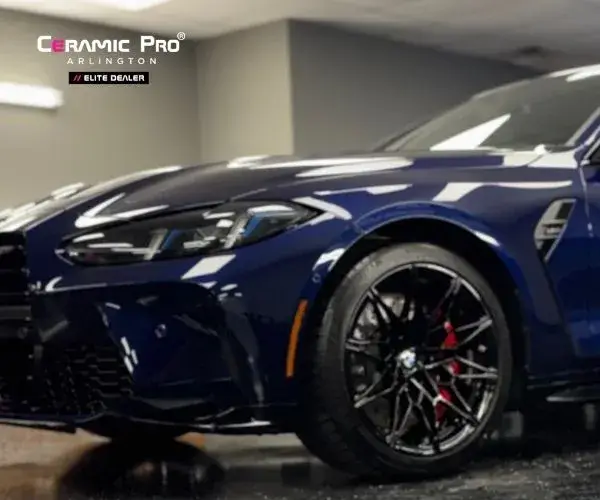 view showing the sleek side profile and glossy dark blue paint of the BMW sports coupe parked under indoor studio lighting.