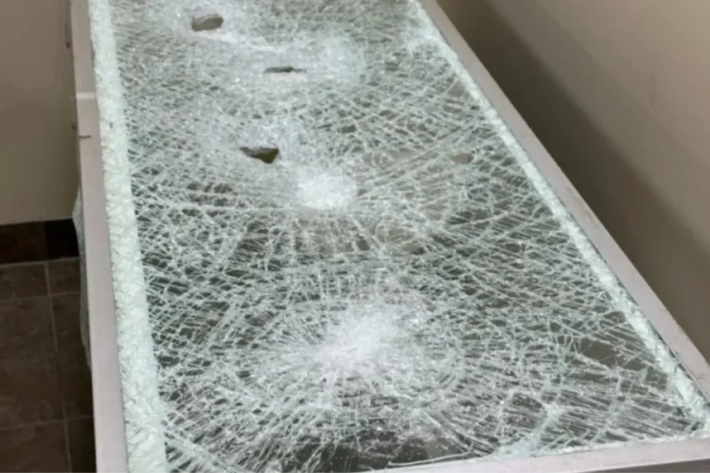 Shattered glass panel held together after impact with protective security window film.
