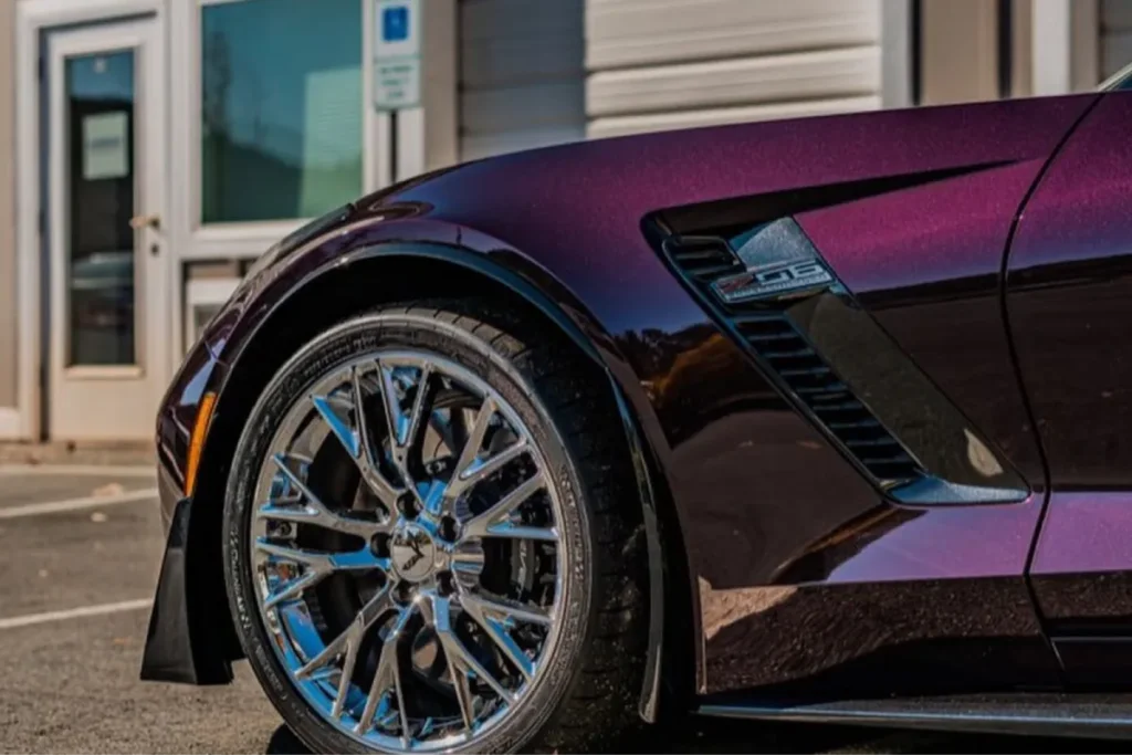 Close-up of a sports car's front fender with a deep purple vinyl wrap.