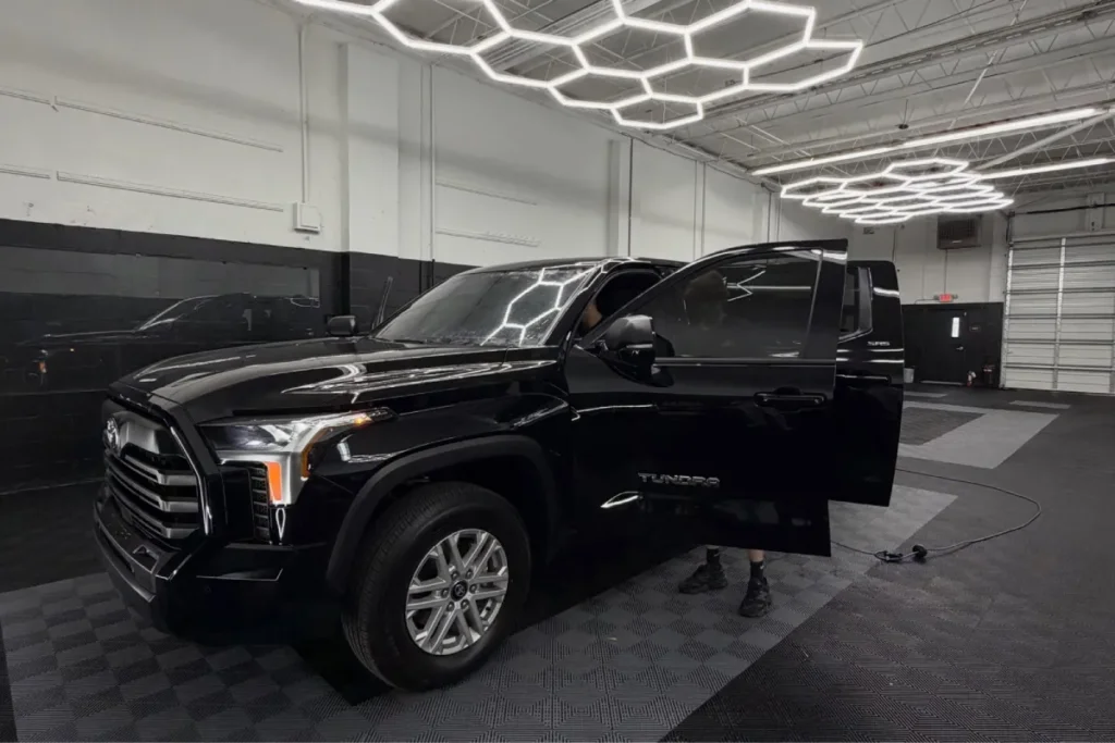 Black Toyota truck with dark window tinting in Jacksonville, FL inside a auto shop.