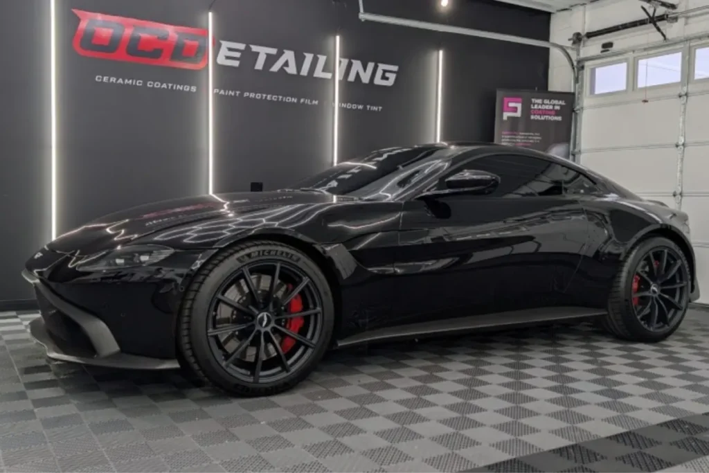 Black sports coupe with dark window tinting parked inside a detailing garage.