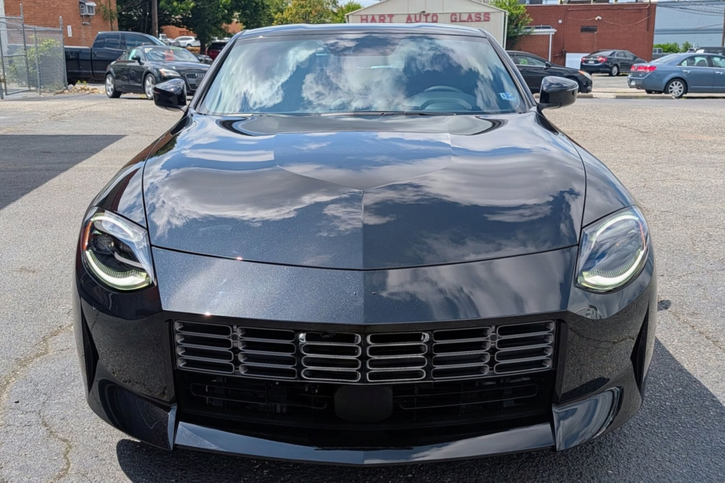 Front view of a shiny black sports car with ceramic coating reflecting the sky.