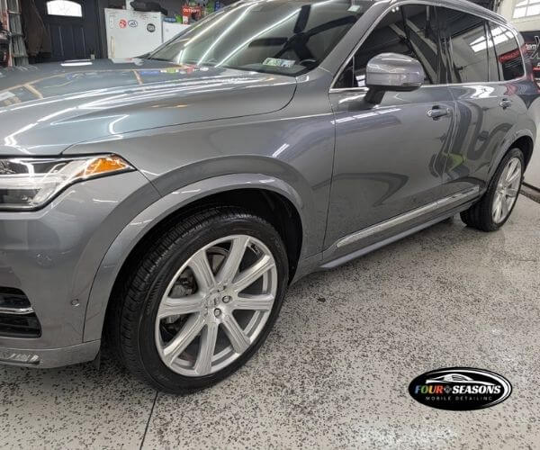Front three-quarter view of a gray luxury SUV parked inside a garage with a speckled floor.