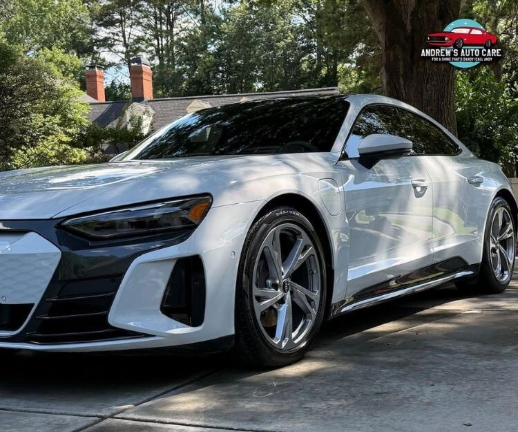 Front three-quarter close-up of a glossy white Audi e-tron GT parked outdoors.