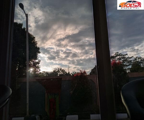 View looking through tinted office windows out toward an outdoor parking area under a cloudy sky.